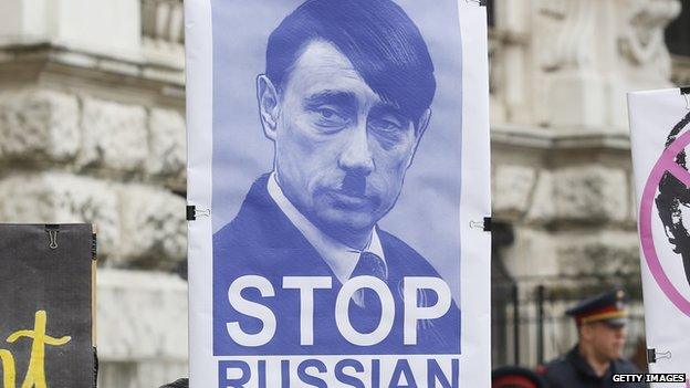 A protestor holds up a sign equating Russian President Vladimir Putin with Adolf Hitler in Vienna on 3 March.