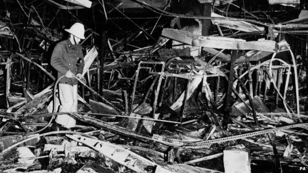 A fireman hoses down smouldered debris inside the Debenhams store at Luton, Befordshire