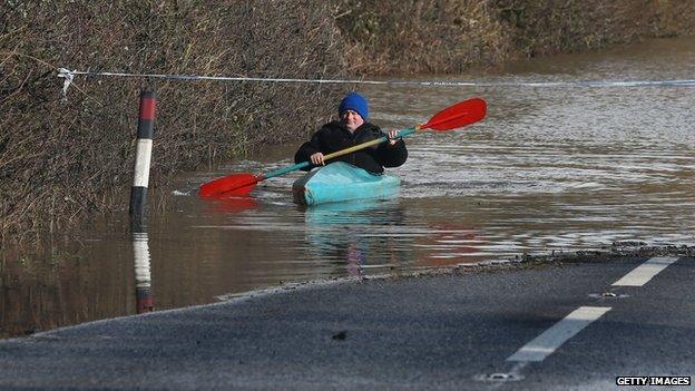 A man paddles his canoe down a flooded road in Somerset