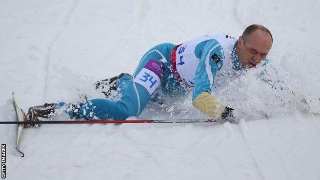 Ukraine's Vitaliy Lukyanenko falls over as he crosses the finish line to win the visually impaired biathlon