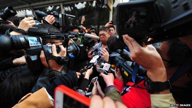 A relative of a passenger onboard Malaysia Airlines flight MH370 is surrounded by journalists at the Metropark Lido Hotel in Beijing, China, on 8 March 2014