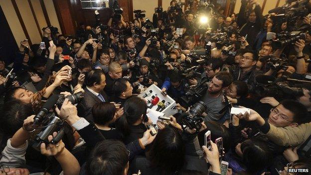 A spokesman (C) of Malaysia Airlines is surrounded by journalists as he gives a briefing about Malaysia Airlines flight MH370, at a hotel in Beijing March 8, 2014