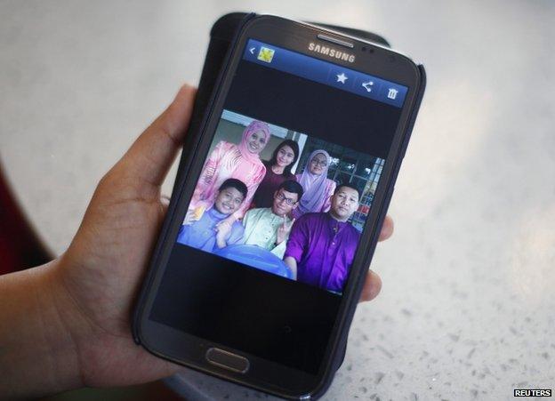 Arni Marlina, 36, a family member of a passenger onboard Flight MH370, shows a family picture on her mobile phone, at a hotel in Putrajaya, Malaysia, 9 March