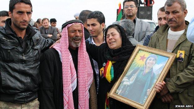 A grieving family attend the funeral of their daughter, who was killed by ISIS fighters