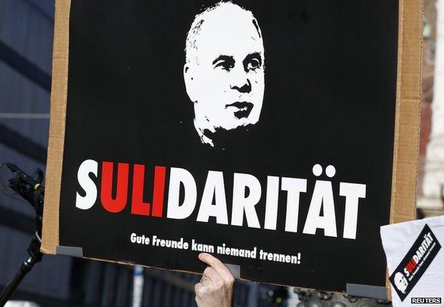 A supporter holds up a placard outside court in Munich (10 March 2014)s