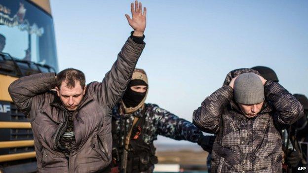 Men are searched by pro-Russian servicemen at Chongar checkpoint blocking the entrance from Ukraine to Crimea