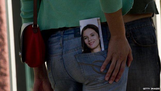 A passer-by carries a pamphlet depicting the New Majority coalition candidate for deputy, Camila Vallejo, during a campaign rally in Santiago on 10 November, 2013