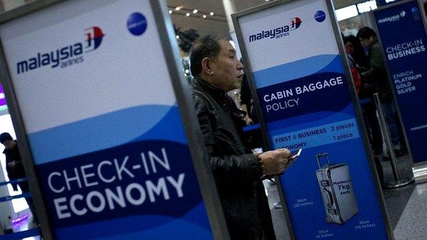 A man presents his passport at a Malaysia Airways check-in counter in Beijing