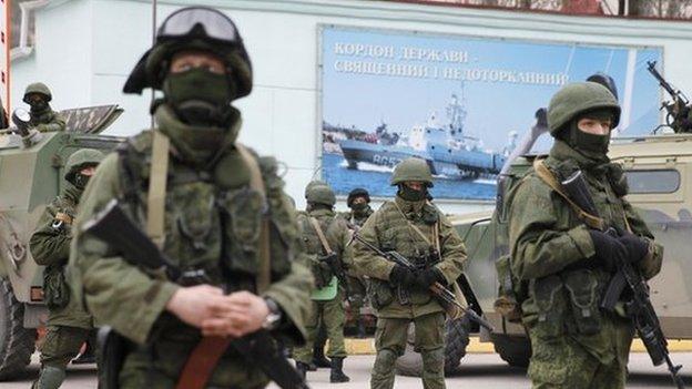 Armed servicemen wait near Russian army vehicles outside a Ukrainian border guard post in the Crimean town of Balaclava March 1, 2014.