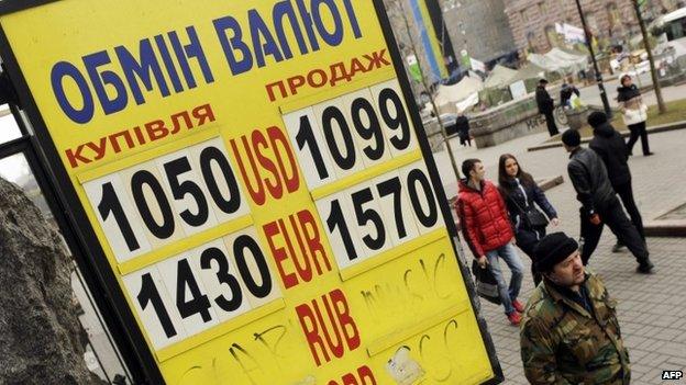 People in Kiev walk past a currency exchange board