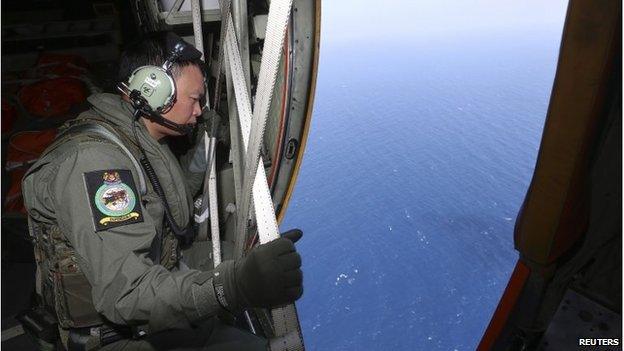 A member of military personnel looks out of a Republic of Singapore Air Force C130 transport plane during the search for the missing Malaysia Airlines plane