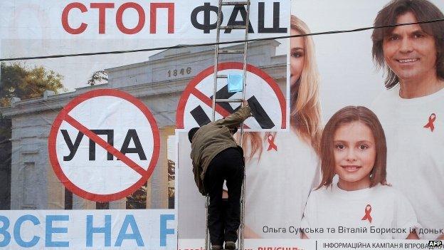 A man posts a on billboard a poster bearing a Nazi swastika and reading "Stop Nazism, all to the referendum" in the Crimean city of Sevastopol