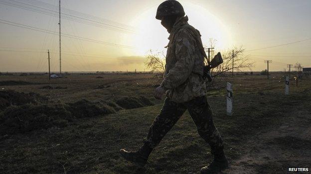 A Ukrainian soldier walks at a checkpoint near the village of Stavki, near the Crimean regional border