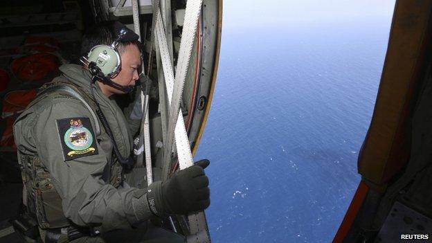 A member of military personnel looks out of a Republic of Singapore Air Force C130 transport plane during a search for the missing Malaysia Airlines MH370 plane over the South China Sea, 11 March 2014
