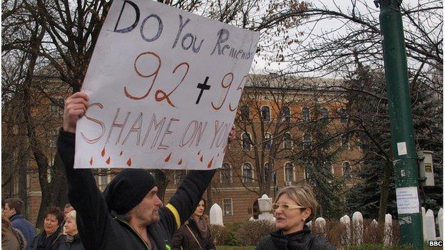 The same protester holding a sign reading "Do you remember 92 + 95? Shame on you"