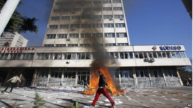 A protester walks past a local government building during protests in Tuzla on 7 February 2014