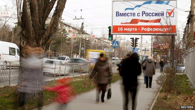 People walk under a referendum poster reading "Together with Russia. March 16 - referendum" in Simferopol on 12 March 2014