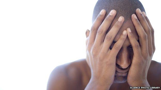 Depressed young man holding his face in his hands