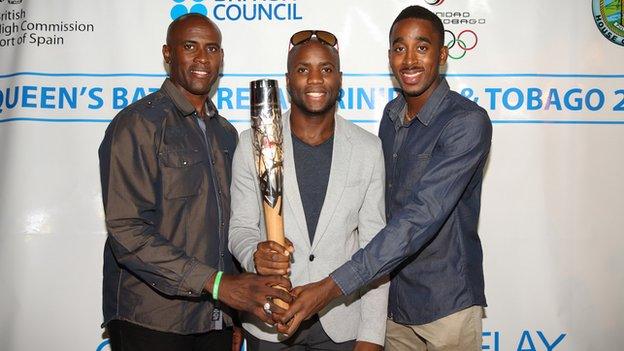 Olympic Games silver and bronze 4x100m medallist Emmanuel Callender (centre) and World Champion 400m hurdler Jehue Gordon (right) hold the Queen's Baton with Commonwealth Games silver and bronze shooting medallist Roger Daniel (left).