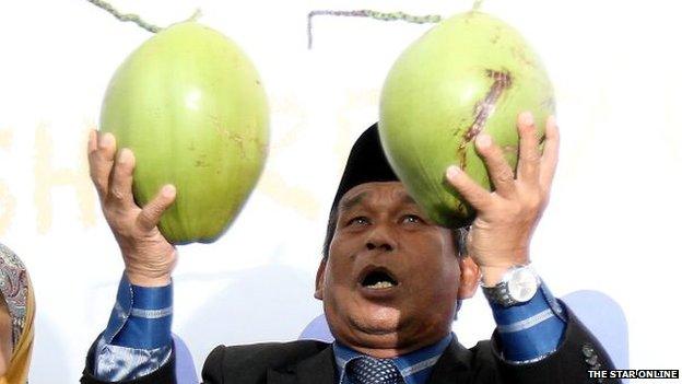 A Malaysian "Bomoh" holding two pieces of fruit