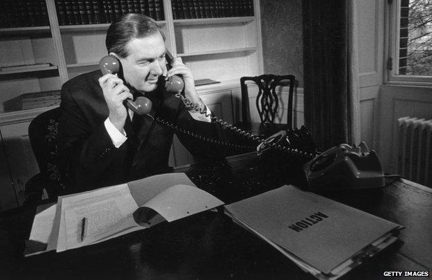 Sitting in his office, Chancellor of the Exchequer in the Labour government, James Callaghan answers two phones at once, on his desk a file marked 'Action' in large letters.