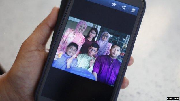 Arni Marlina, 36, a family member of a passenger onboard the missing Malaysia Airlines flight MH370, shows a family picture on her mobile phone, at a hotel in Putrajaya 9 March 2014. Marlina's stepbrother Muhammad Razahan Zamani (bottom, right), 24, and his wife Norli Akmar Hamid, 33, were on their honeymoon on the missing flight