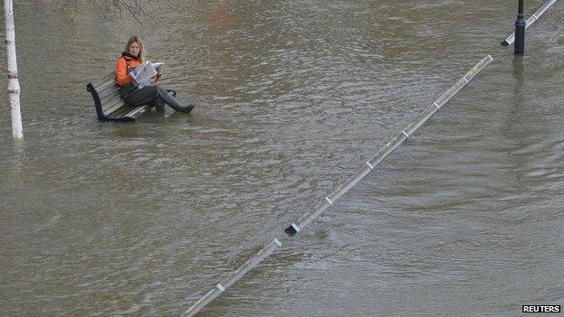 Woman sitting in floodwater in Staines