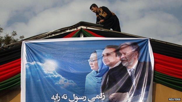 Supporter of Afghan presidential candidate Zalmai Rassoul hangs poster.