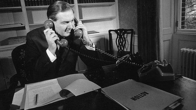 Sitting in his office, Chancellor of the Exchequer in the Labour government, James Callaghan answers two phones at once, on his desk a file marked 'Action' in large letters.