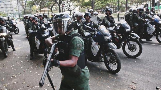 A Bolivarian National Guard aims his weapon while searching for anti-government demonstrators after they dispersed from Plaza Altamira in Caracas on 16 March, 2014