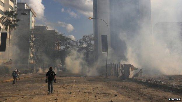 Anti-government protesters walk amidst teargas during a protest against Nicolas Maduro's government at Altamira square in Caracas on 16 March, 2014