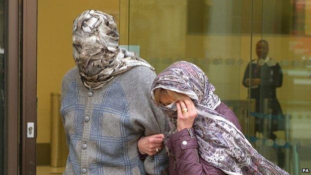 Domenico Rancadore and his wife hide their faces as they are perused by journalists