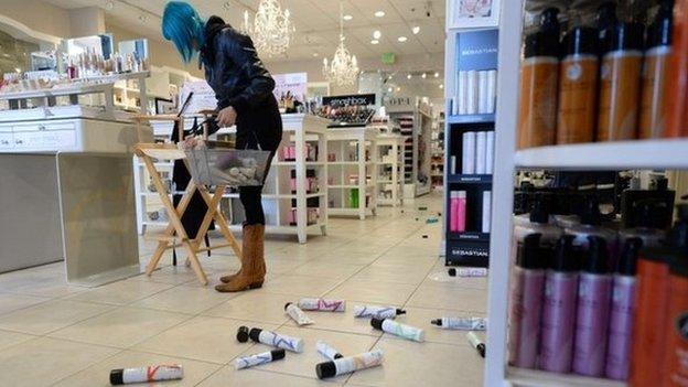 Employee Paula Anania cleans up hair care products that were knocked off the shelf in a beauty supply store in the Encino area of Los Angeles after a 4.4 earthquake jolted the area on 17 March 2014