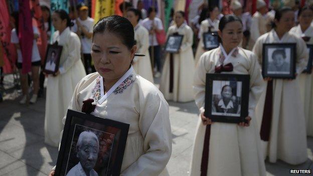 Participants carry the portraits of Korean women who were made sex slaves by the Japanese military during World War II, during a requiem ceremony for former comfort woman Lee Yong-nyeo in central Seoul, 14 August 2013