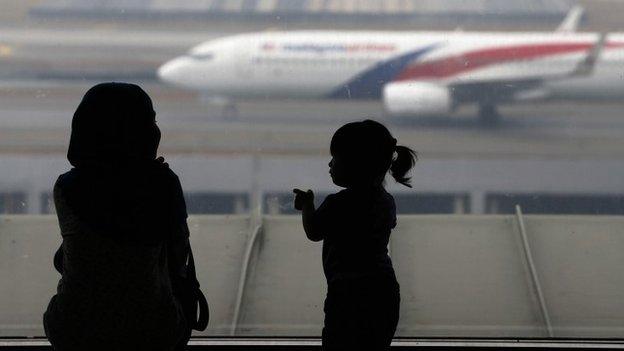 A woman and a girl look at a Malaysia Airlines plane