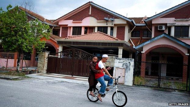 Boys cycle past the house of Fariq Abdul Hamid (16 March 2014)