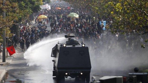 A police water cannon releases a jet of water on student protesters in Chile, April 2013