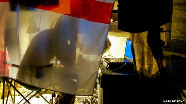 A man screens himself behind a flag at Camp Bastion