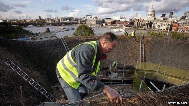 A worker fixes the roof of the Globe Theatre, London