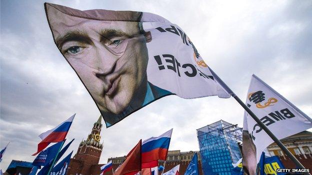 Pro-Kremlin activists wave a flag depicting President Vladimir Putin at rally at the Red Square in Moscow, on 18 March 2014, to celebrate the incorporation of Crimea