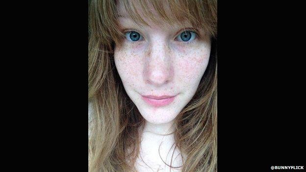 A woman wearing no makeup takes a selfie