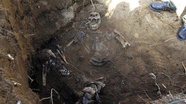 A forensic technician stands next to the remains of a person