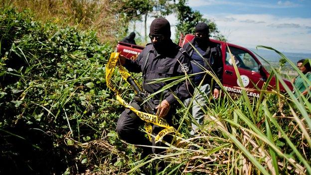 Police investigators secure the site of an unmarked grave