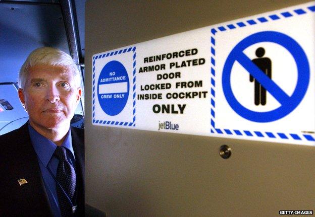 Chief pilot of JetBlue Airways Lanny McAndrew, stands behind one of the new bullet-force-resistant cockpit doors that have been installed on all JetBlue planes after the September 11 attacks, October 17, 2001