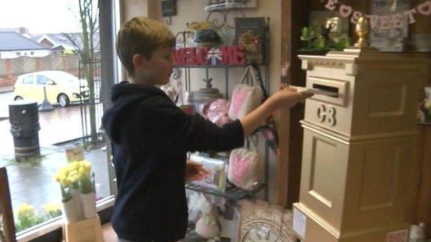 Boy posting letter into gold post box