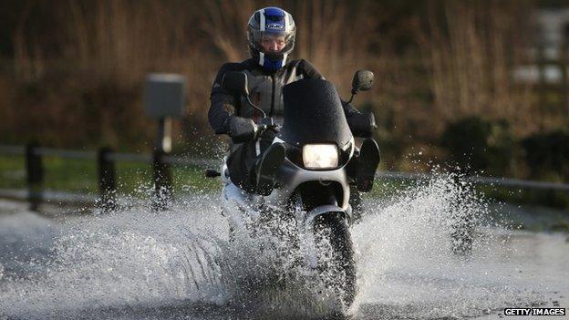 Motorcyclist riding through floodwater in Chertsey