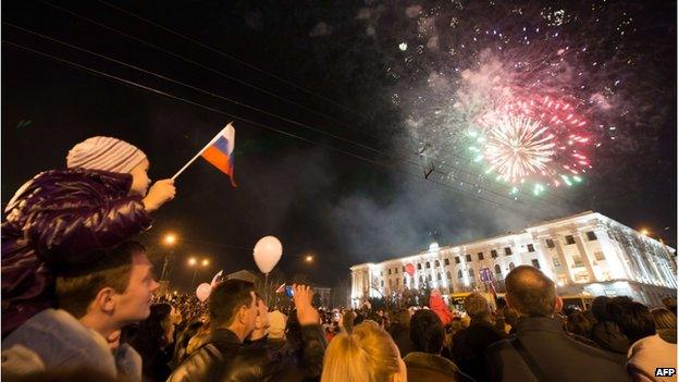 A young boy waves a Russian flag as people look at fireworks in the Crimean city of Simferopol (21 March 2014)