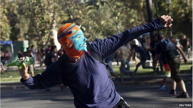 Masked protester in Chile throwing bottle