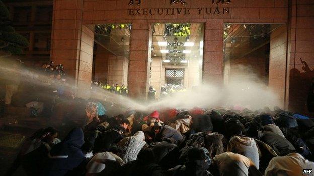 Protesters are sprayed with a water cannon during a demonstration outside the Executive Yuan in Taipei early on 24 March 2014