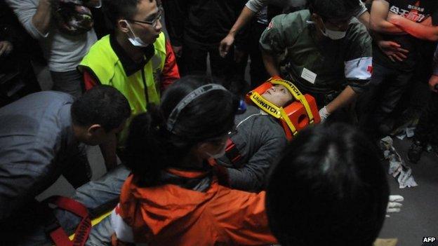 Paramedics carry an injured protester on a stretcher at the Executive Yuan in Taipei early on 24 March 2014